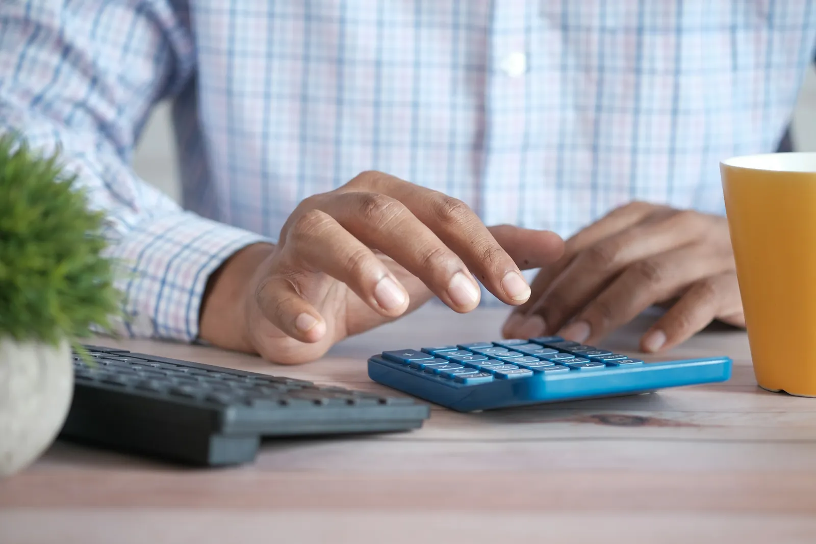 Persona usando una calculadora en su escritorio, junto al teclado